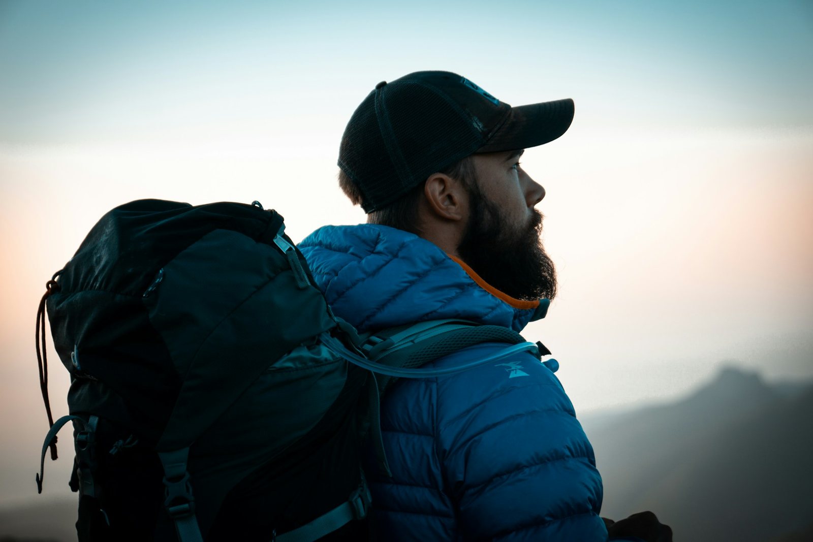 Senderista con mochila y chaqueta de plumas azul al amanecer
