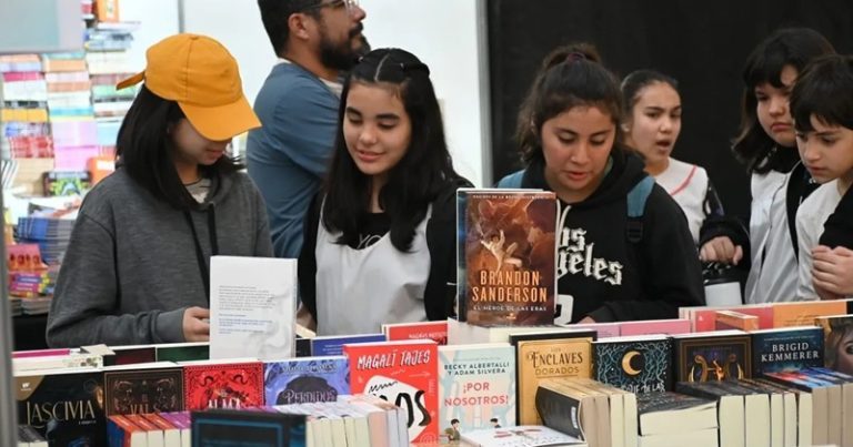 Estudiantes mirando libros en un stand de la feria