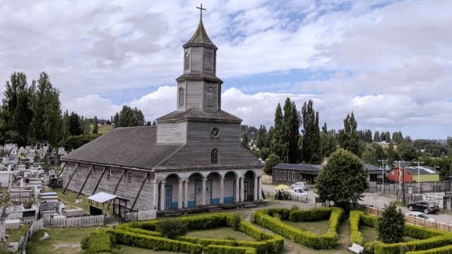 Iglesia de madera de Chiloé con torre y pórtico de arcos, vista desde el aire